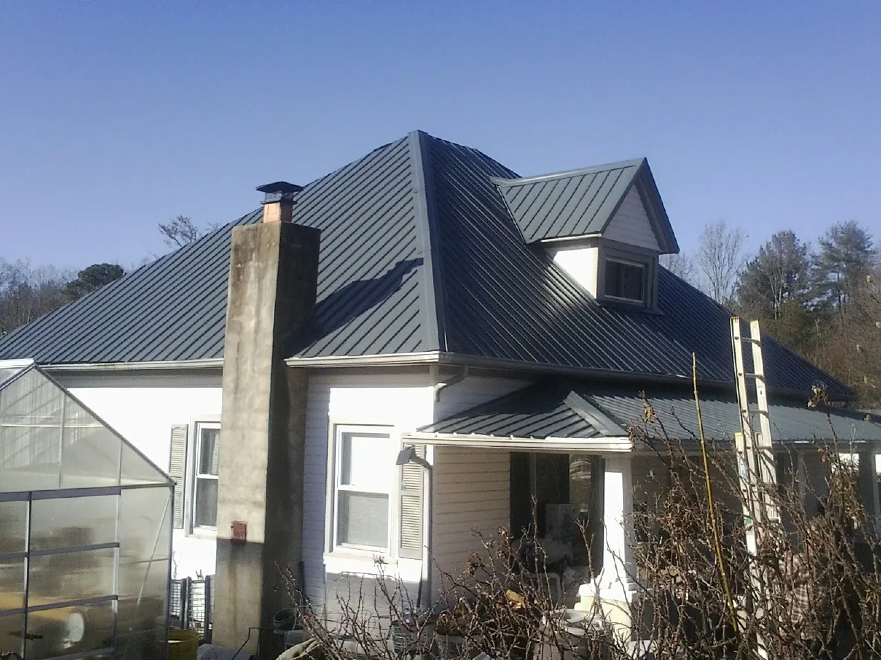Dark blue standing seam metal roof on a white farmhouse with dormer — Slate & Tile Roof Repair by Roofing Brothers in Putnam