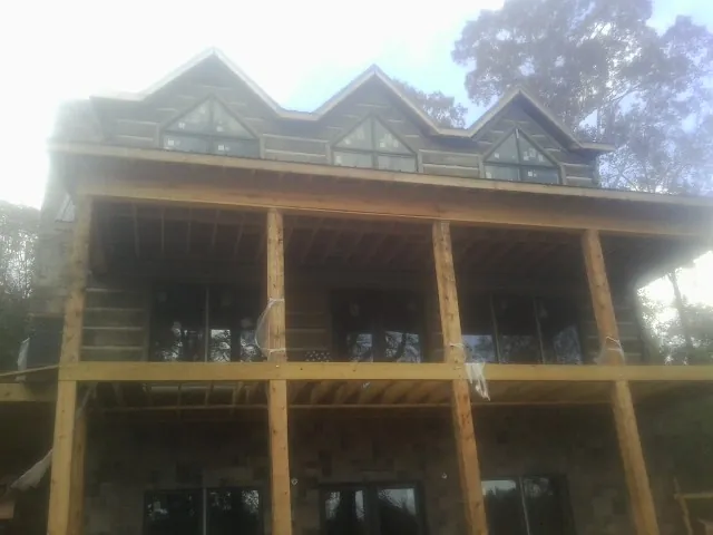 Dormers and porch framing on a large log home under construction — Roof Coating work by our crew in Putnam