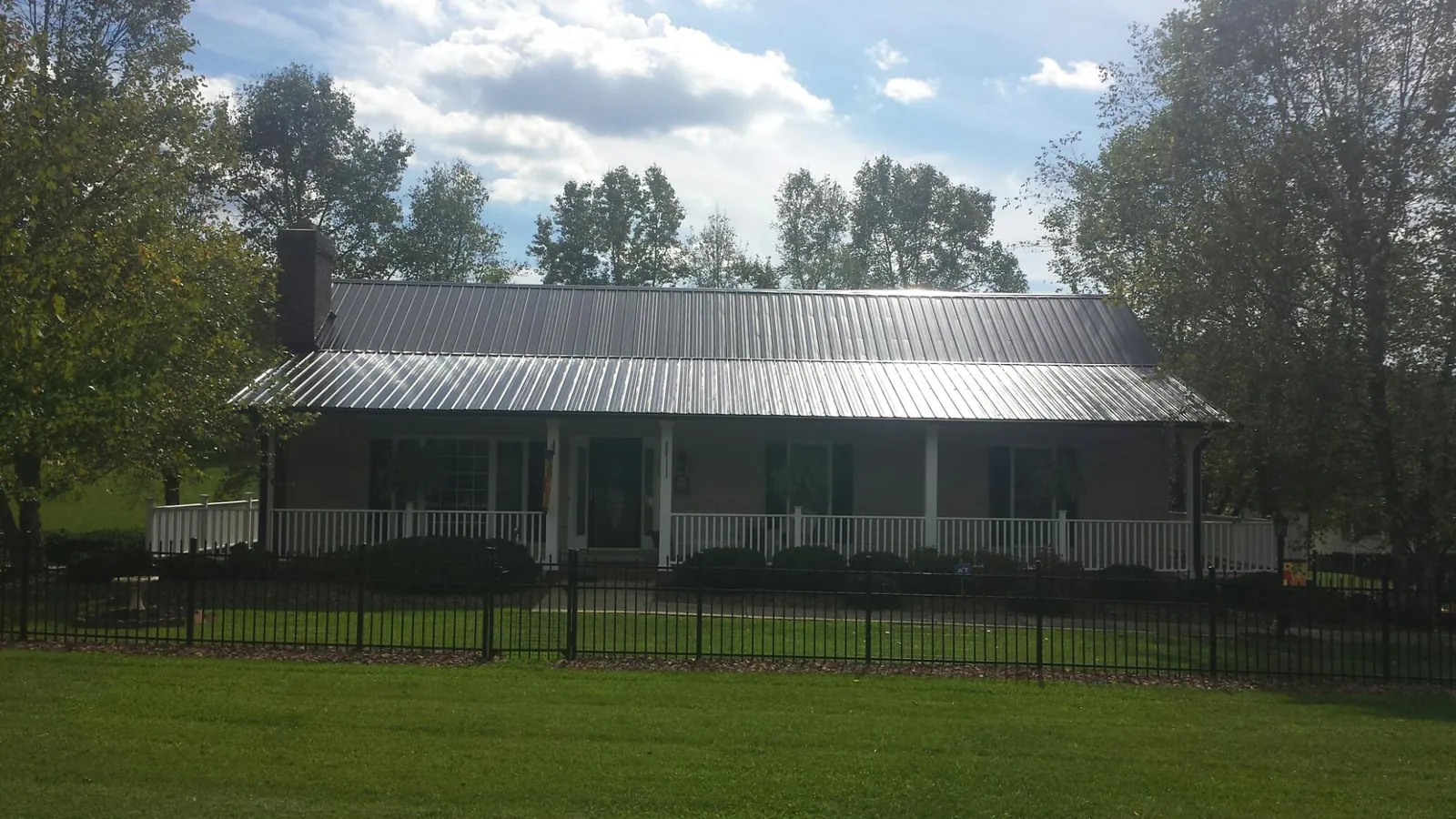 Gray metal roof on a brick ranch with a full width front porch — Gutter Guard Installation work by our crew in Putnam