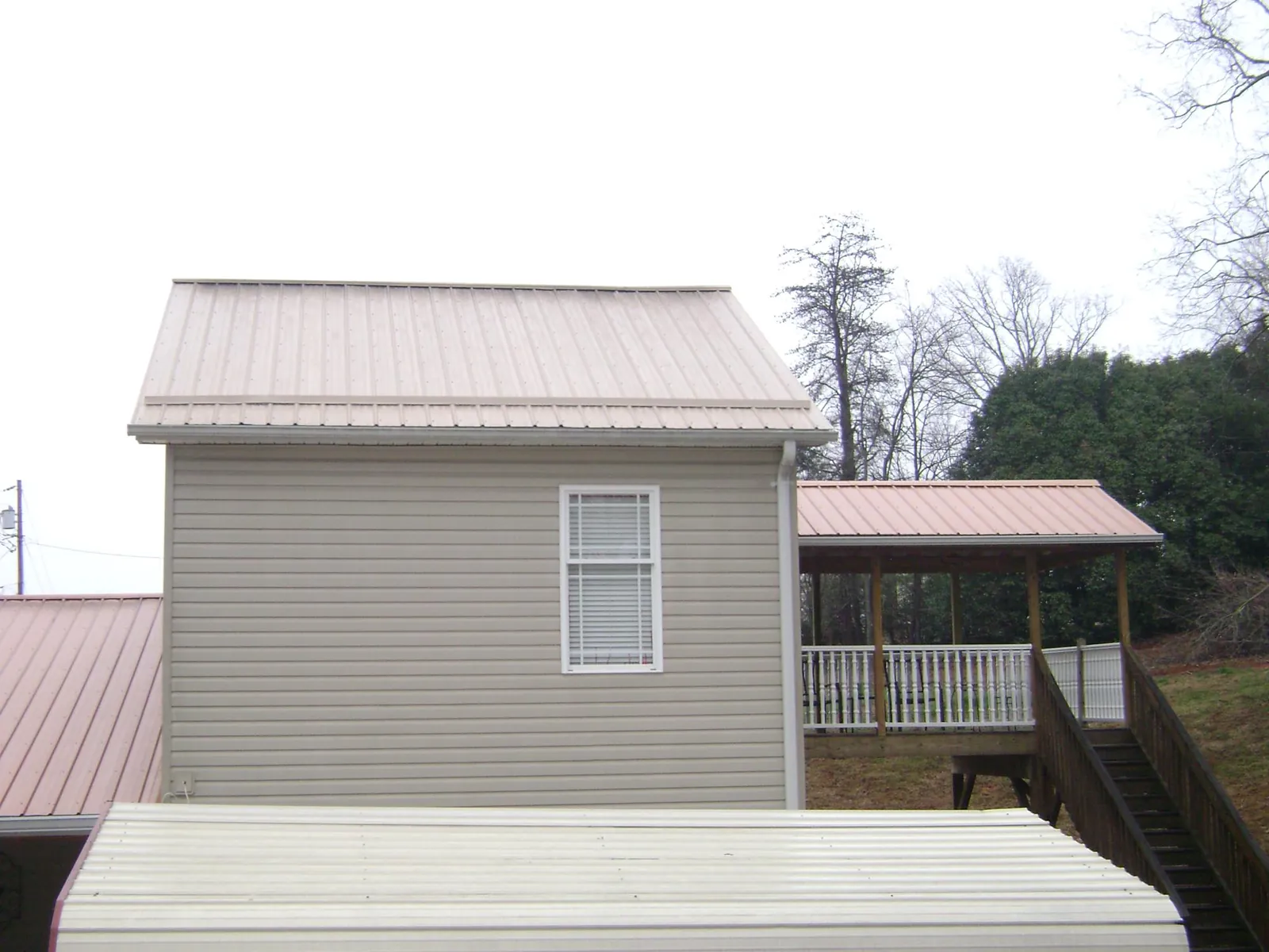 Tan metal roofs on a two story addition and attached porch, from a Roof Replacement job in Putnam