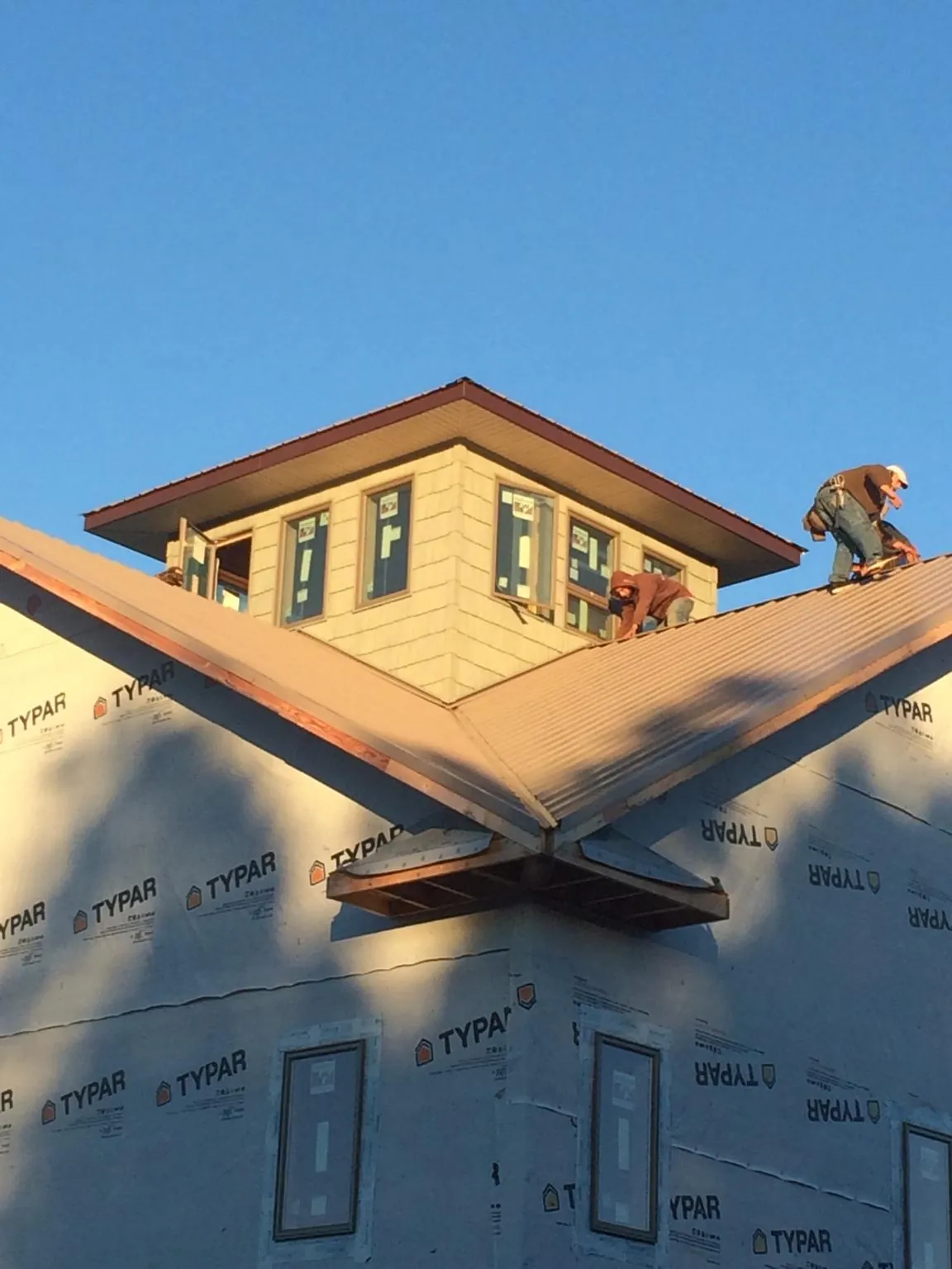 Roofers working around a rooftop cupola on a new metal roof at sunset — Roof Waterproofing in Putnam by Roofing Brothers